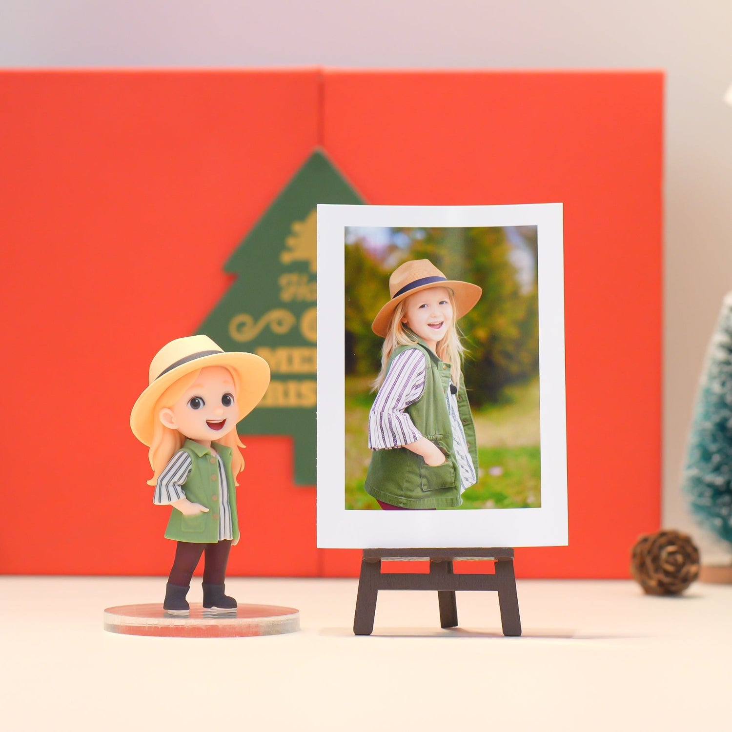 Figurine of a girl in a green outfit with a hat, standing next to a photo frame displaying a picture of a girl in a similar outfit.