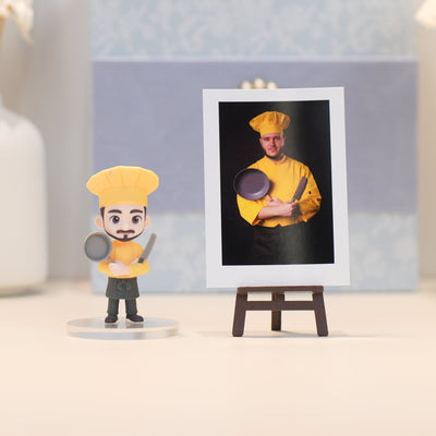 Chef figurine next to a framed photo of a chef holding a pan and knife on a stand.