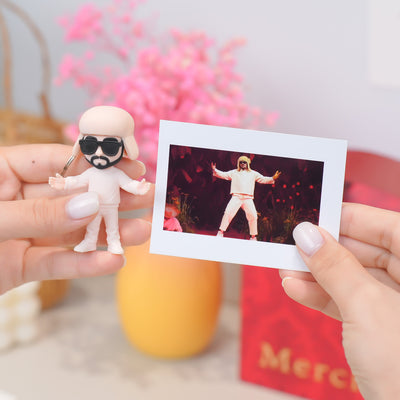 Person holding a figurine and a photo of a person in a costume with pink flowers in the background
