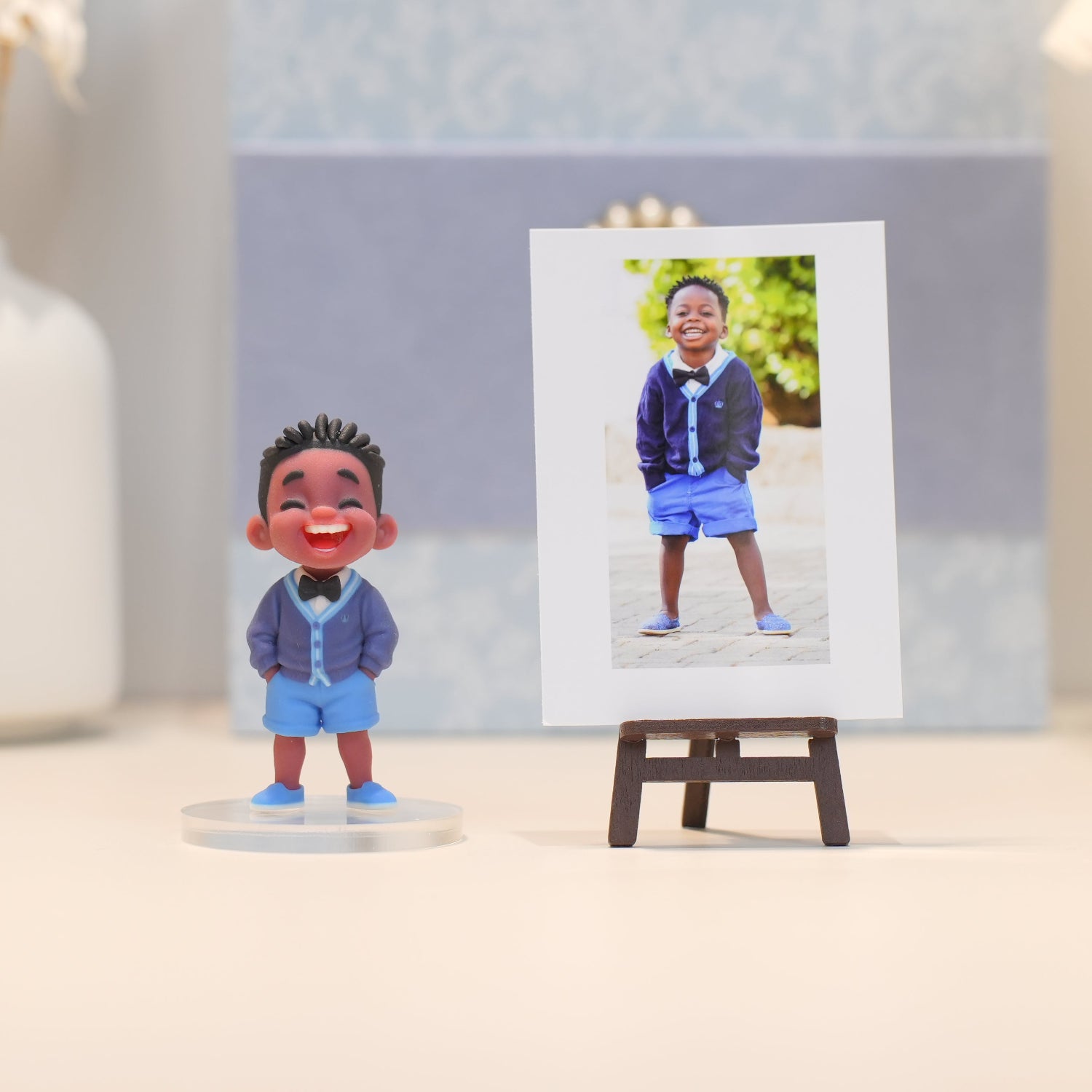 Small figurine of a child in a blue outfit next to a photo of the same child outdoors.