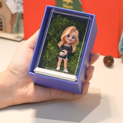 Hand holding a small figurine in a purple box with a Christmas-themed background