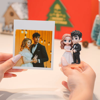 Hand holding a photo of a couple next to a matching cake topper with a similar design.