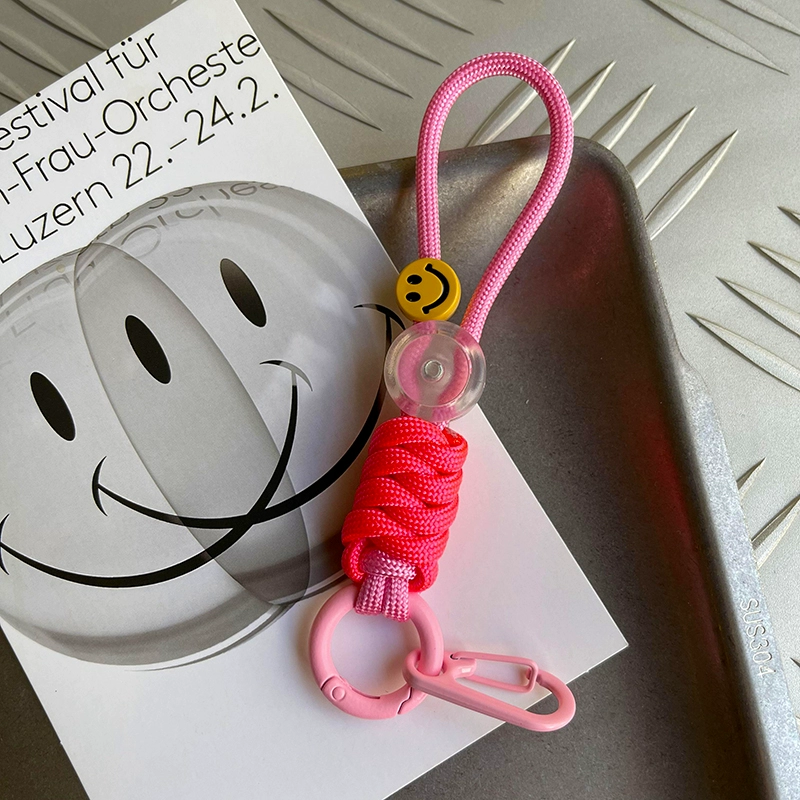 Pink keychain with a smiley face charm on a white surface