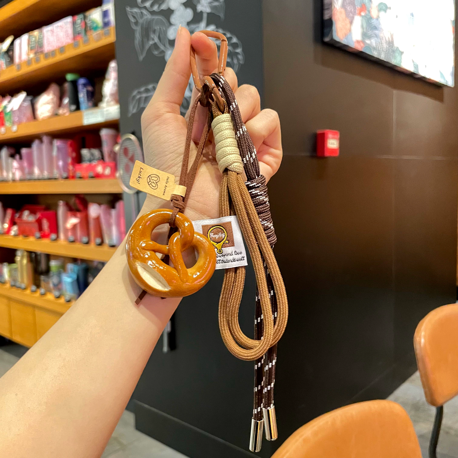 Hand holding a keychain with a pretzel-shaped charm in a store setting
