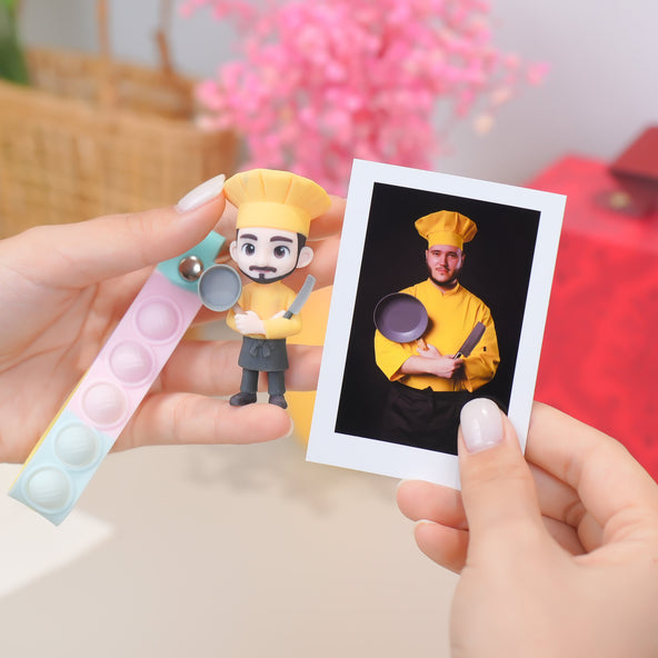 Person holding a cartoon character magnet and a photo of a person in a yellow chef outfit.