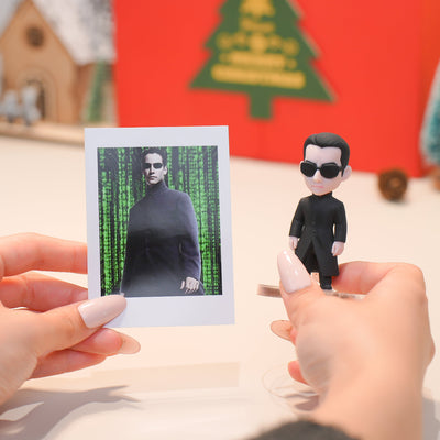 Bobblehead figure of a character from a movie held next to a photo of the same character.