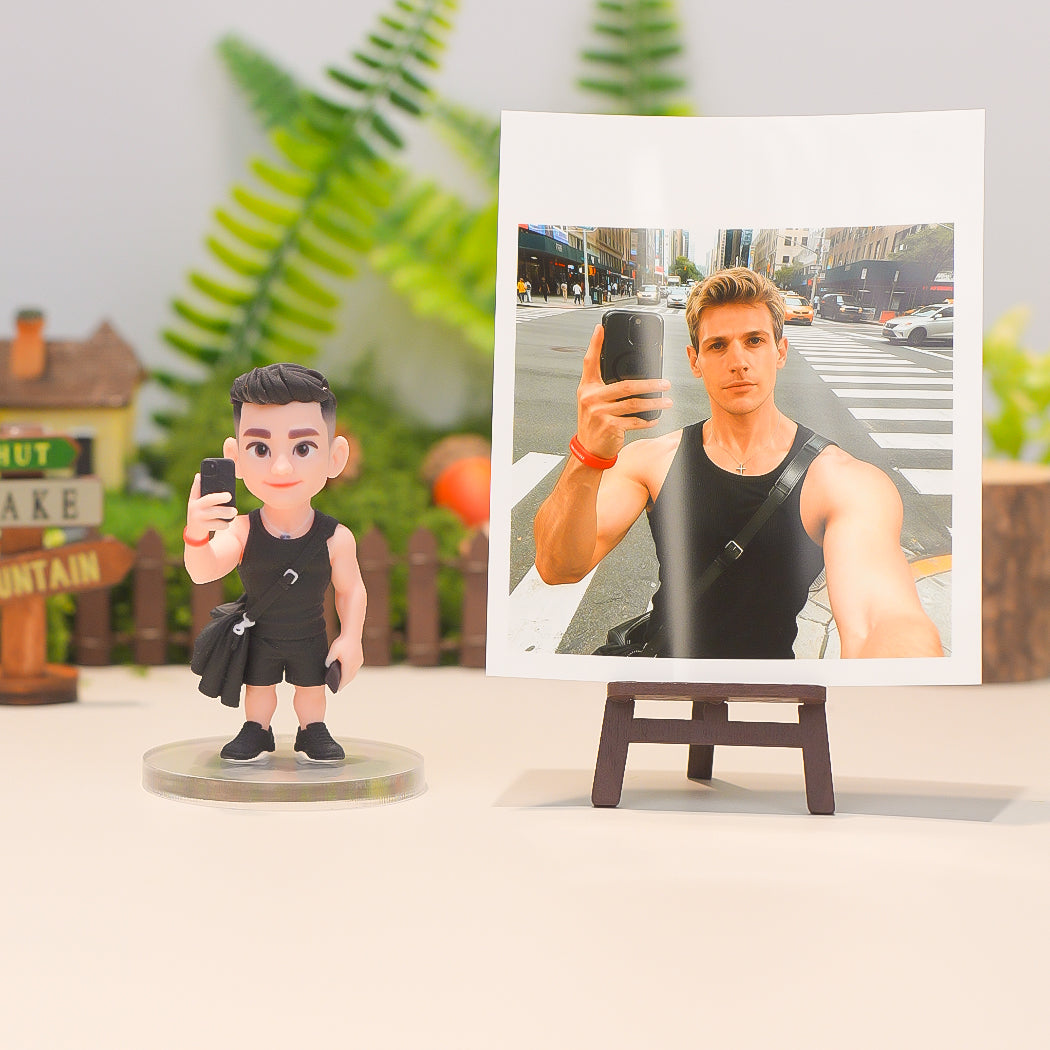 Bobblehead figure of a person taking a selfie with a photo of the same person on a stand.