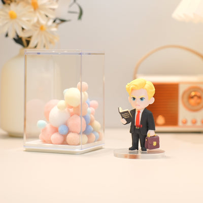 Figurine of a man in a suit holding a briefcase next to balloons in a glass box.