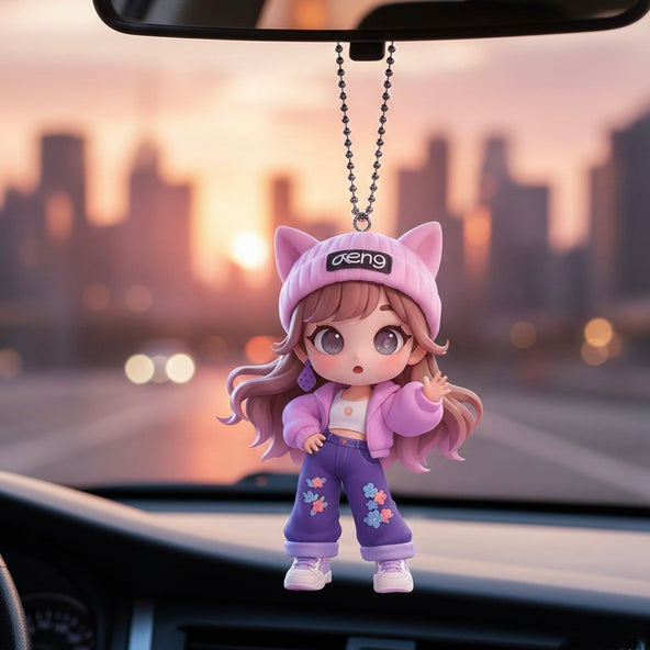Cartoon character keychain with cat ears hanging from a car's rearview mirror with a cityscape in the background.