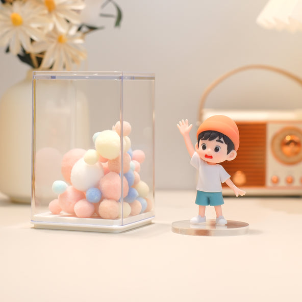 Figurine of a boy with balloons in a glass display case on a light surface.