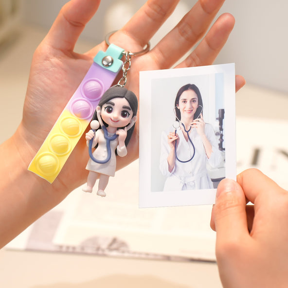 Keychain with a small figure of a doctor held by a hand, next to a photo of a person in a medical setting.
