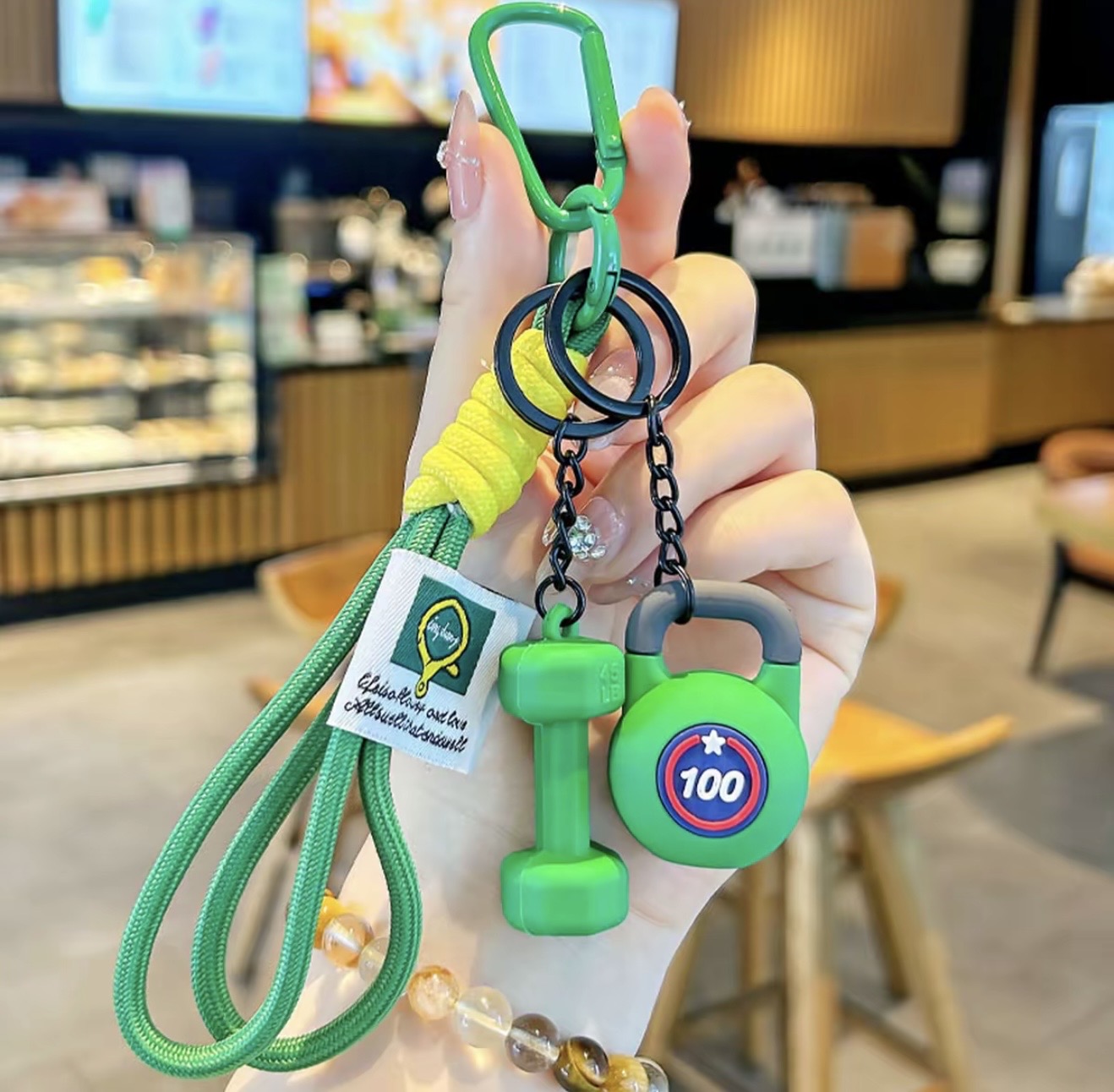 Green keychain with fitness-themed design held in a hand inside a store.