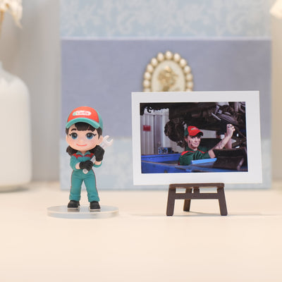 Figurine of a character in a green uniform and red cap next to a photo on a stand.