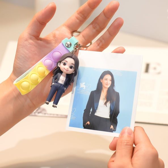 Keychain with a women character and a photo card held by a hand