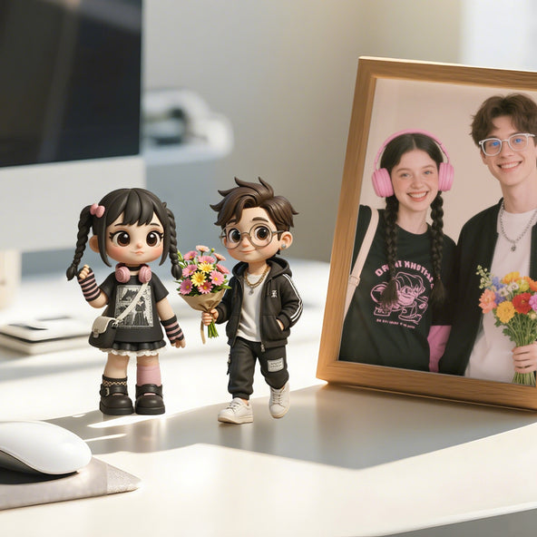 Two figurines of a boy and girl with a framed photo of two people on a desk.