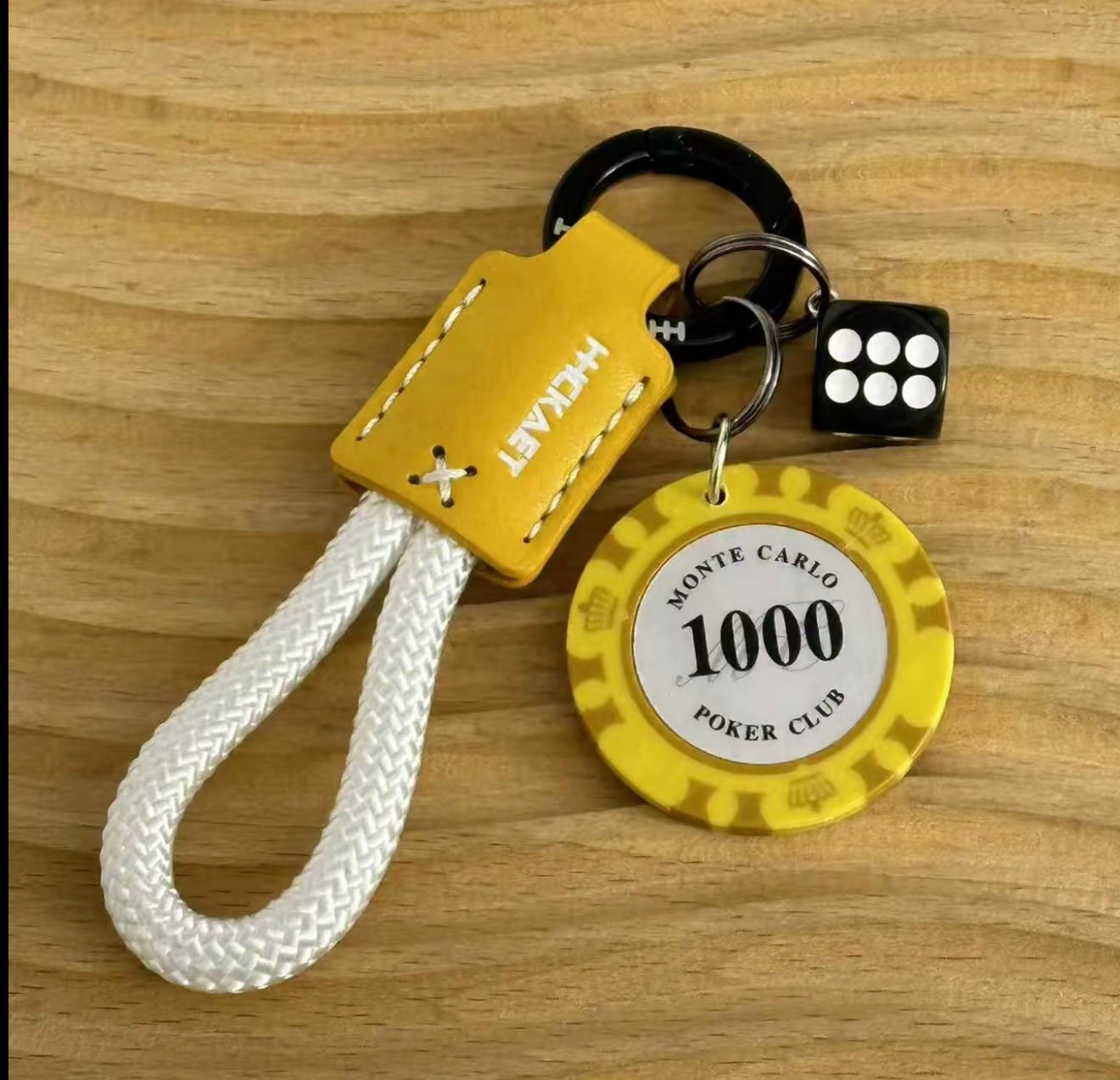 Keychain with yellow tag, dice, and poker chip on a wooden surface