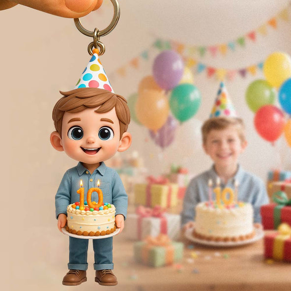 Keychain of a cartoon boy with a birthday cake and candles, with a blurred background of a birthday party.
