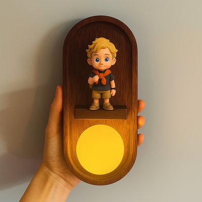Wooden night light with a figurine of a boy holding a heart, held by a hand against a neutral background.