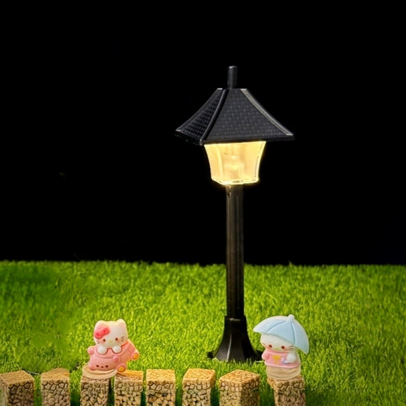 Decorative garden lamp with small animal figurines on wooden blocks against a black background