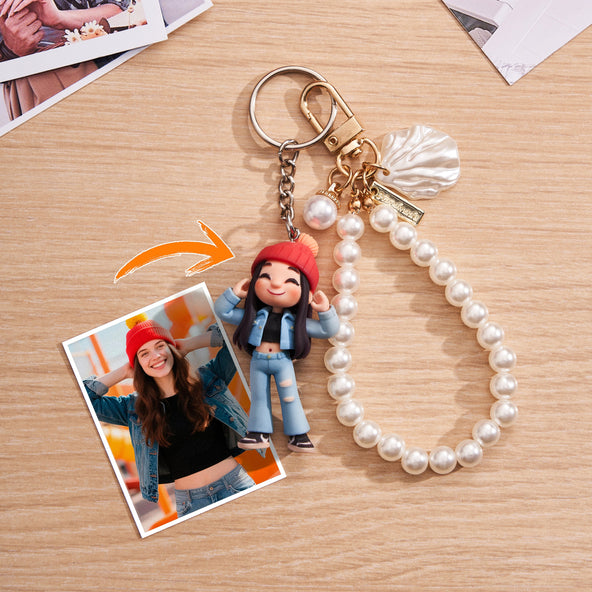 Keychain with a figurine and pearl bracelet on a wooden surface, with a photo of a person wearing a red hat and blue jeans.