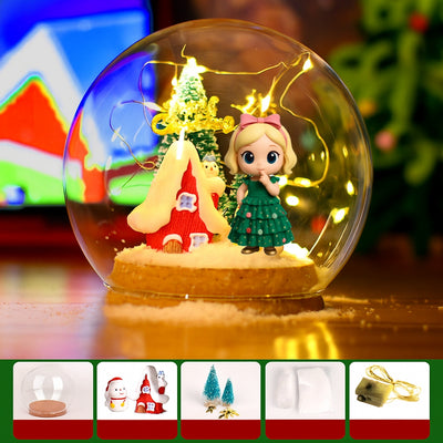Decorative glass ball with Christmas scene including a house, tree, and figurine.