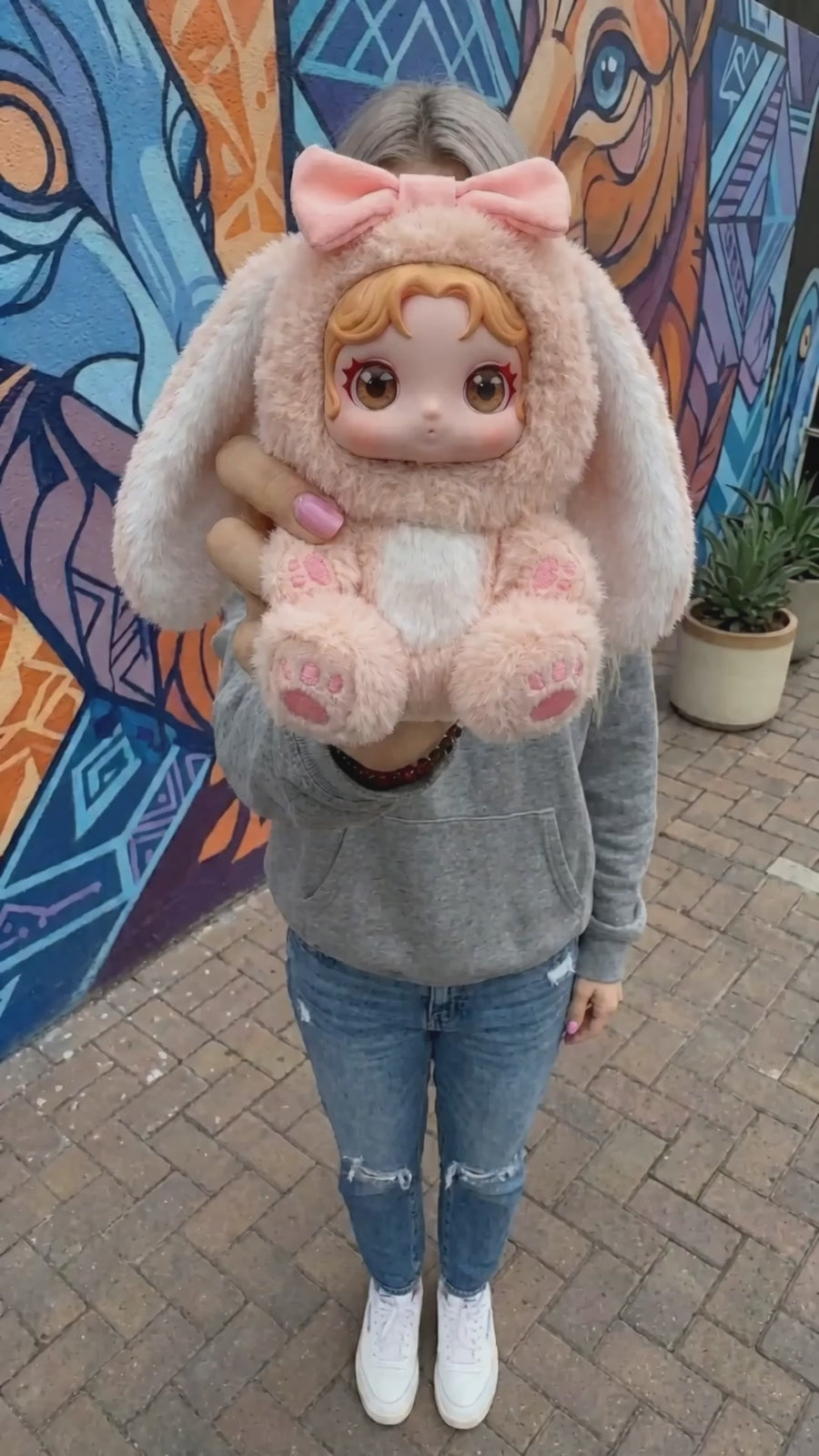 Custom plush doll shown against a blue sky backdrop in a product video